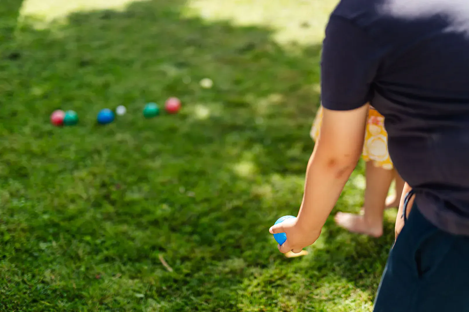 Colorful bocce balls resting on a grass court near the small target pallino, the kind of set that makes the best bocce ball set