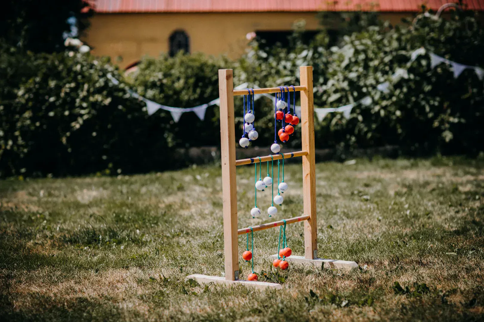 A ladder ball set with three rungs on a backyard lawn and bolas wrapped around the top rung, the kind of set that makes the best ladder ball set