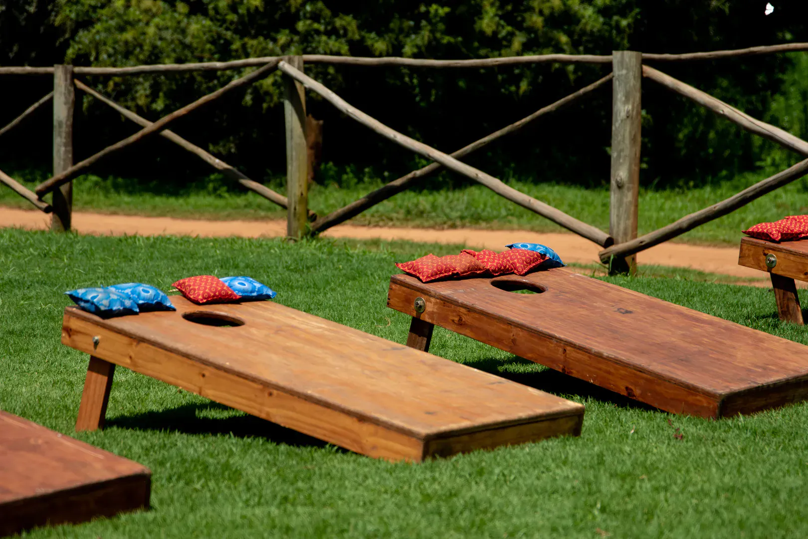 Wooden cornhole boards with colorful regulation cornhole bags on a sunny green lawn