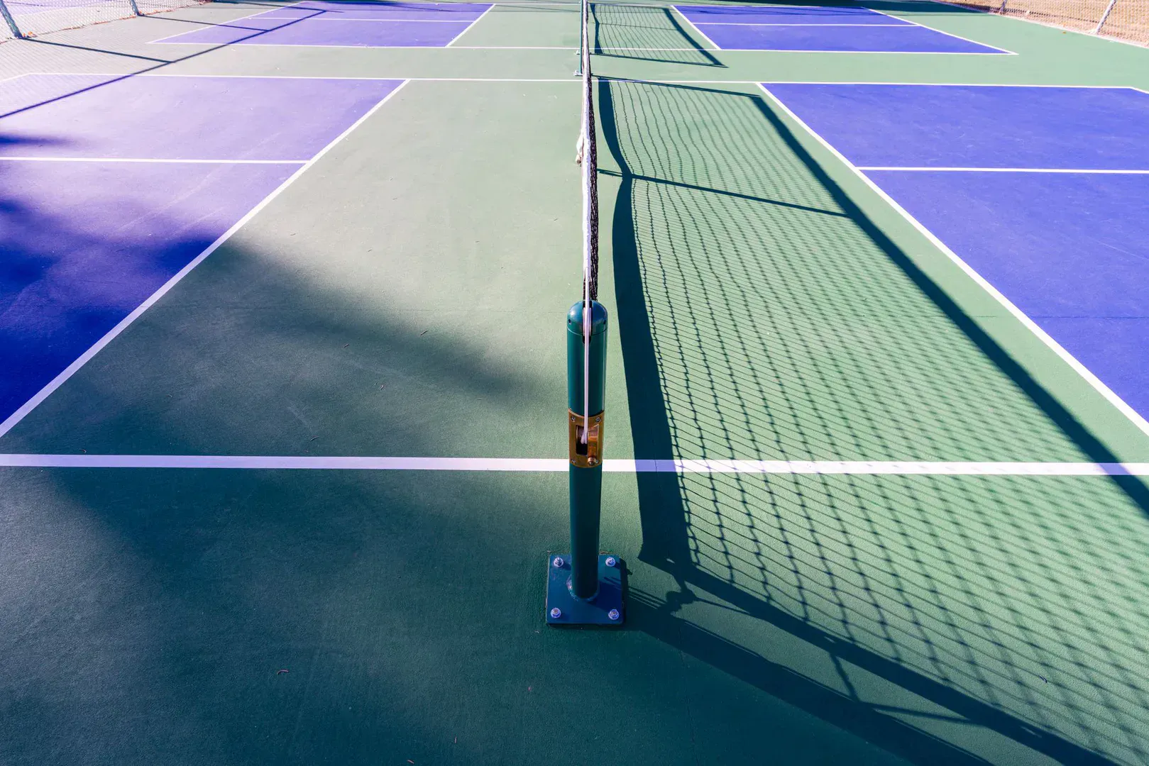 A backyard pickleball court taped out on a driveway with a portable net set up