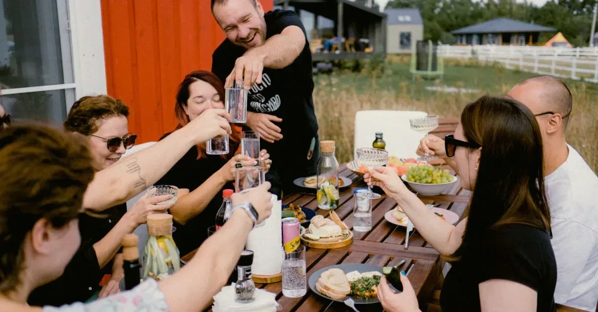 Adults laughing and playing the best outdoor party games for adults with drinks at a backyard get-together